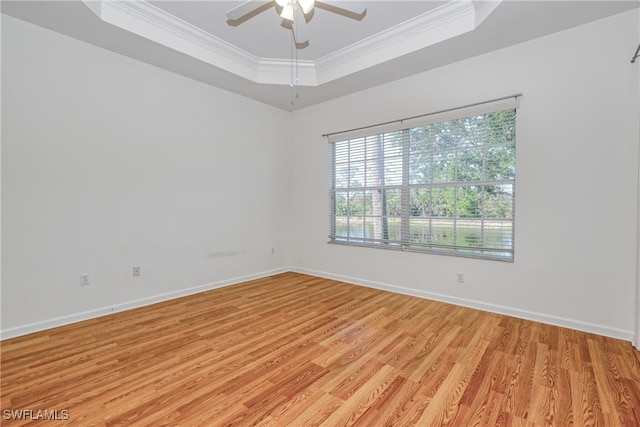 empty room featuring ceiling fan, ornamental molding, a raised ceiling, and light wood-type flooring