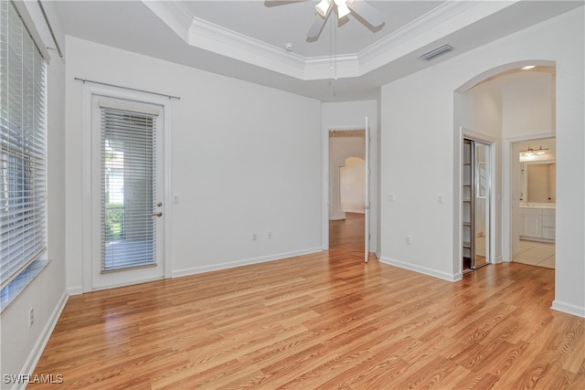 unfurnished room featuring ornamental molding, a raised ceiling, ceiling fan, and light wood-type flooring