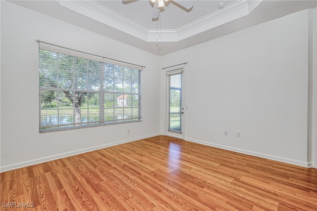 unfurnished room featuring a raised ceiling, crown molding, ceiling fan, and light hardwood / wood-style flooring