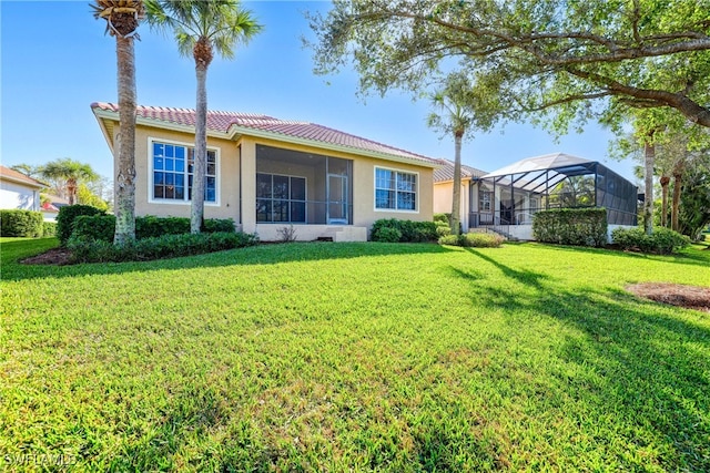 rear view of property featuring a lanai and a lawn