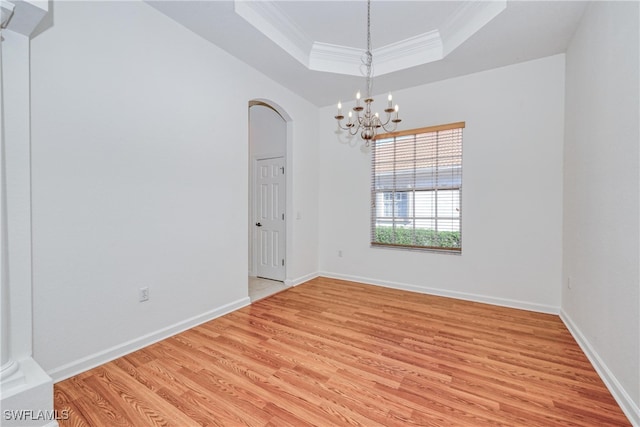 unfurnished room featuring crown molding, a raised ceiling, light hardwood / wood-style floors, and a notable chandelier