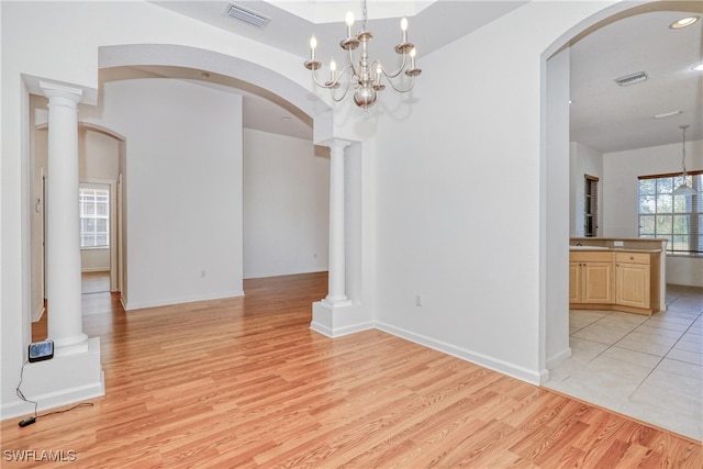 interior space featuring a notable chandelier, sink, light hardwood / wood-style flooring, and ornate columns