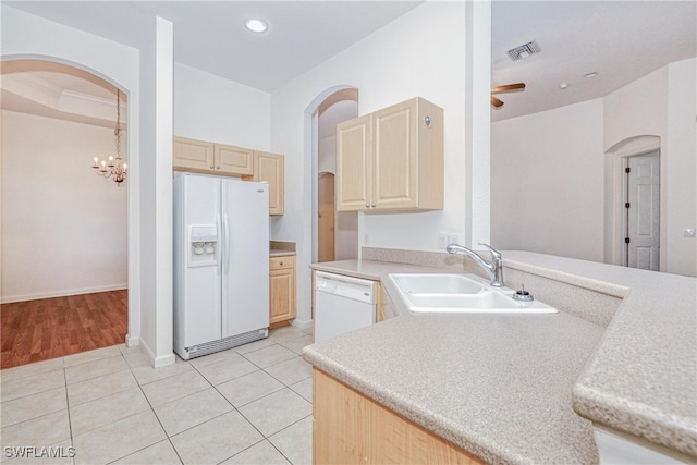 kitchen with white appliances, light brown cabinetry, and sink