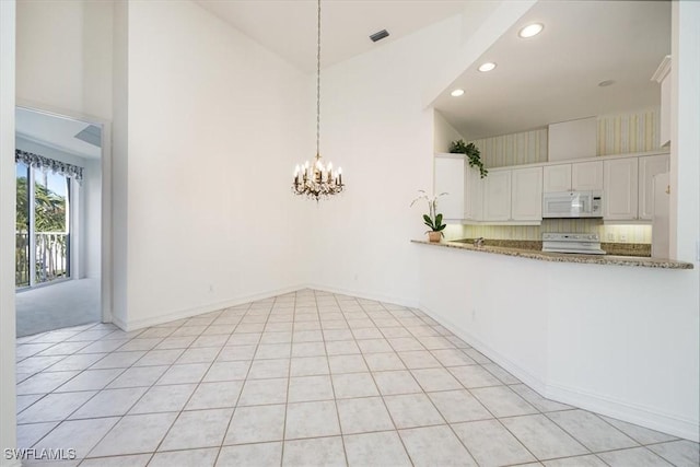 1575 Clermont Dr Unit N-201, Naples, FL 34109 - unfurnished dining area with a towering ceiling, a chandelier, and recessed lighting
