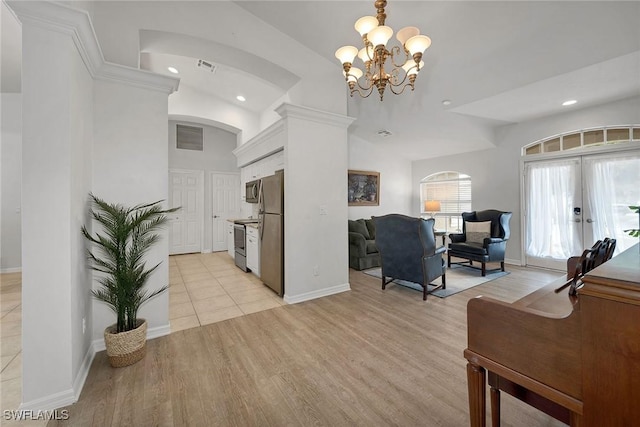 kitchen with french doors, a towering ceiling, stainless steel appliances, light hardwood / wood-style flooring, and a chandelier