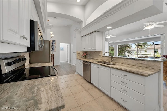 kitchen with sink, backsplash, ceiling fan, appliances with stainless steel finishes, and white cabinets