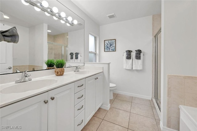 bathroom featuring tile patterned flooring, vanity, toilet, and walk in shower