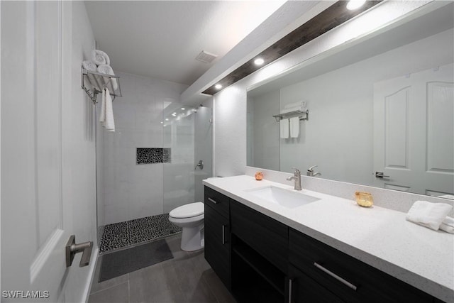 bathroom with vanity, toilet, and a tile shower