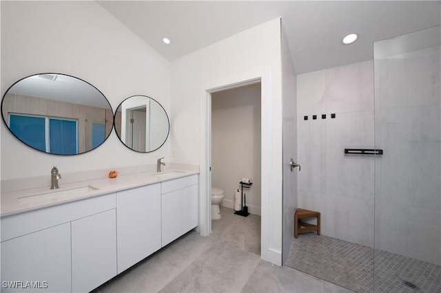 bathroom with vanity, lofted ceiling, tiled shower, and toilet