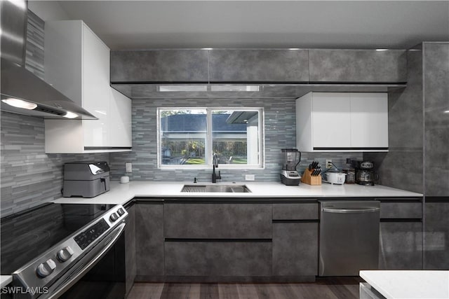 kitchen with sink, white cabinetry, tasteful backsplash, appliances with stainless steel finishes, and wall chimney range hood