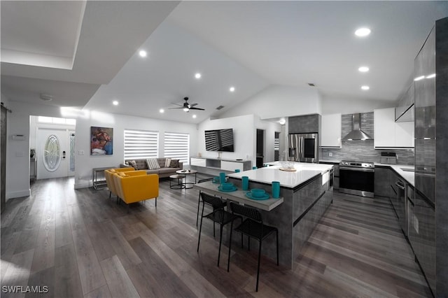 dining area with high vaulted ceiling, dark hardwood / wood-style floors, ceiling fan, and a barn door