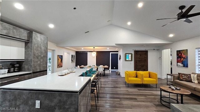 kitchen with hanging light fixtures, a barn door, a center island, and dark hardwood / wood-style flooring