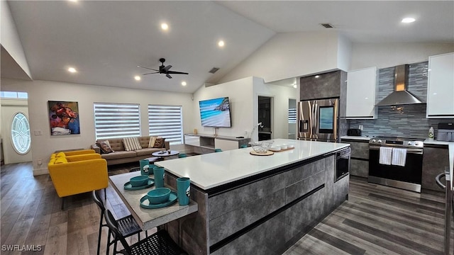 kitchen with a kitchen island, white cabinetry, stainless steel appliances, dark wood-type flooring, and wall chimney range hood