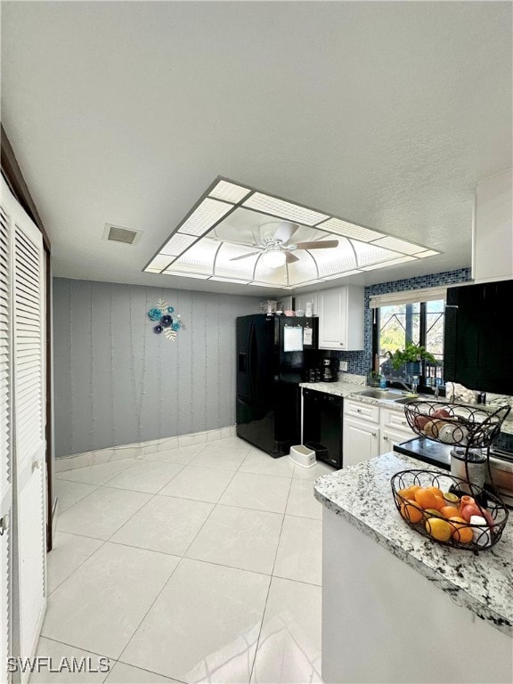 kitchen featuring sink, white cabinetry, light stone countertops, light tile patterned flooring, and black refrigerator with ice dispenser