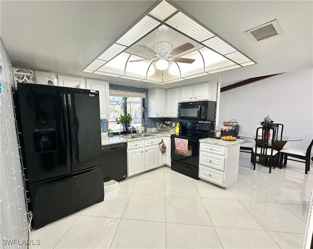 kitchen with light tile patterned flooring, white cabinets, decorative backsplash, light stone counters, and black appliances