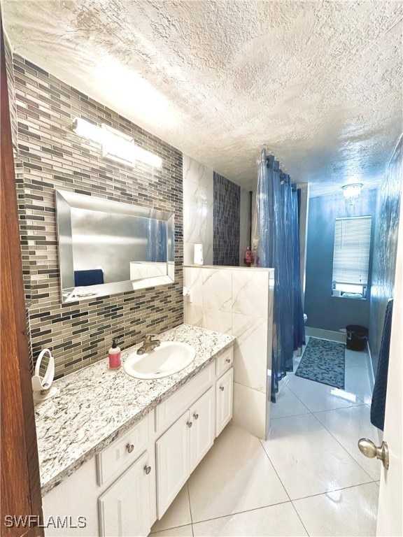 bathroom featuring vanity, tile patterned flooring, a textured ceiling, and backsplash