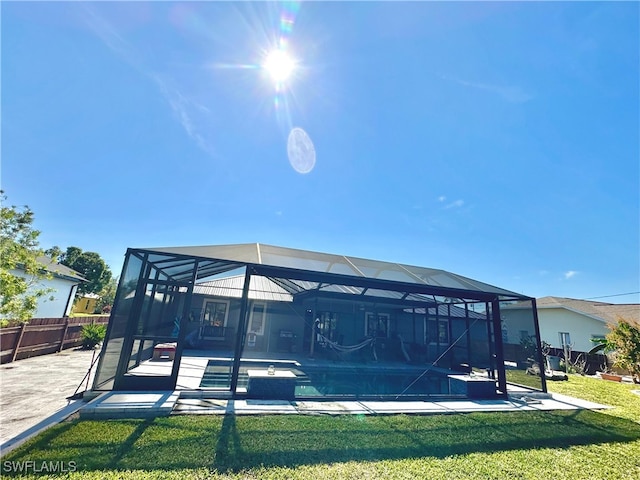 back of property with a yard, a patio, and glass enclosure