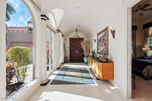 hall featuring vaulted ceiling, decorative columns, and light tile patterned flooring