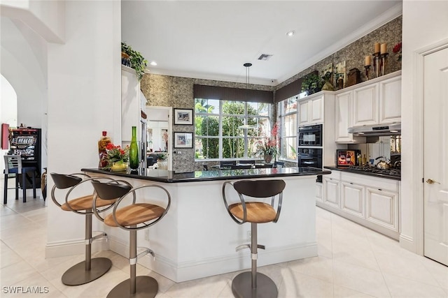 kitchen with a breakfast bar area, decorative light fixtures, white cabinets, stainless steel gas stovetop, and backsplash