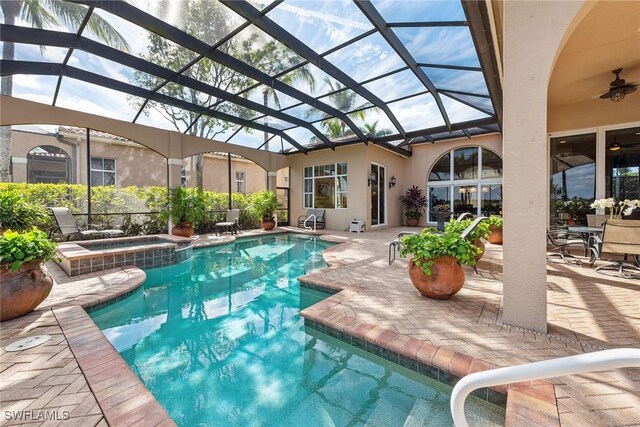 view of pool with an in ground hot tub, ceiling fan, a patio, and glass enclosure