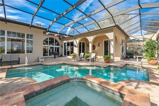 view of pool with an in ground hot tub, glass enclosure, and a patio