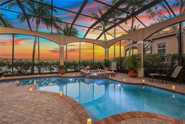 pool at dusk featuring a patio area and an in ground hot tub