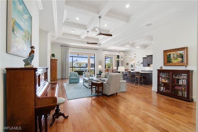 living room featuring beamed ceiling, ornamental molding, coffered ceiling, ceiling fan, and light hardwood / wood-style floors