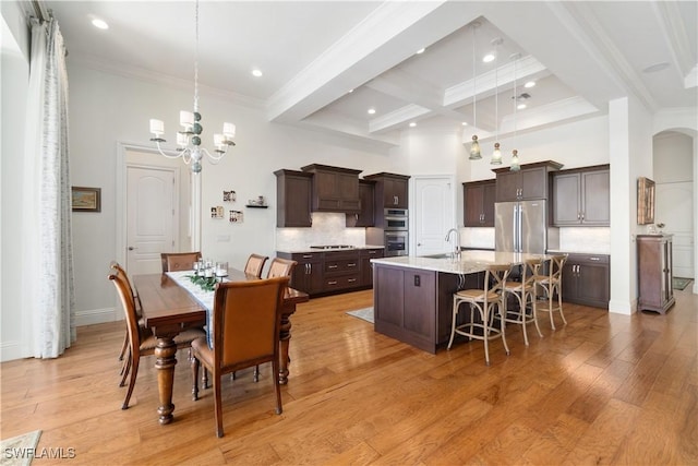 dining area with a towering ceiling, sink, coffered ceiling, light hardwood / wood-style floors, and beam ceiling