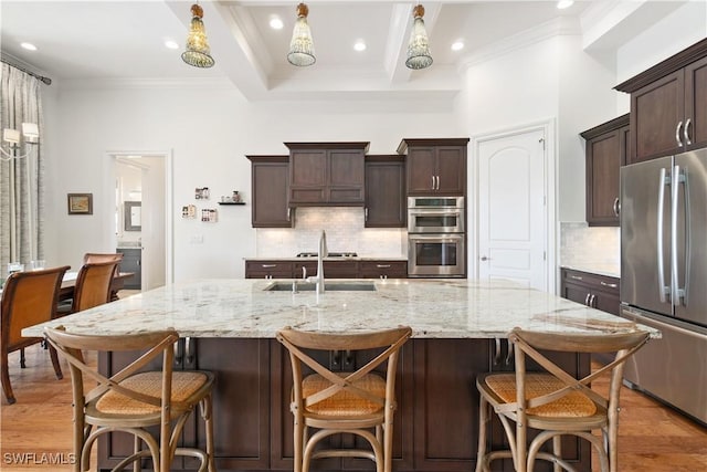 kitchen featuring appliances with stainless steel finishes, sink, light hardwood / wood-style flooring, and a large island