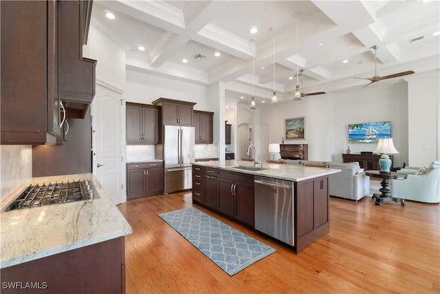 kitchen featuring sink, light hardwood / wood-style flooring, appliances with stainless steel finishes, an island with sink, and a high ceiling