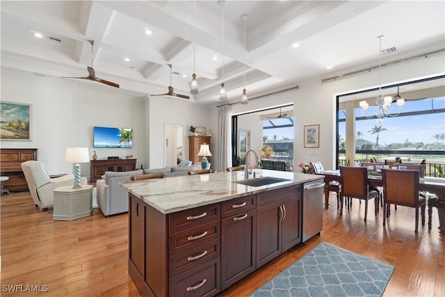 kitchen with stainless steel dishwasher, an island with sink, sink, and hanging light fixtures