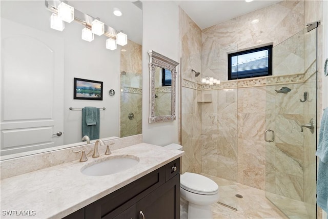 bathroom featuring toilet, vanity, and a shower with shower door