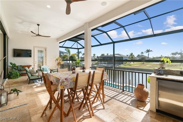 sunroom with a water view and ceiling fan