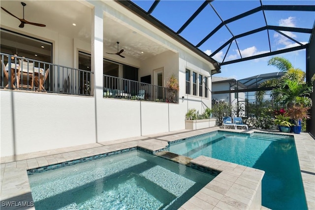 view of pool with an in ground hot tub, a patio, ceiling fan, and glass enclosure