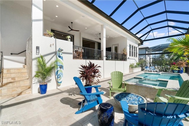 view of pool with a patio area, glass enclosure, ceiling fan, and an in ground hot tub