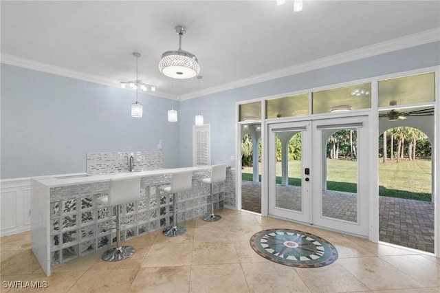 interior space with french doors, bar, ornamental molding, and light tile patterned floors