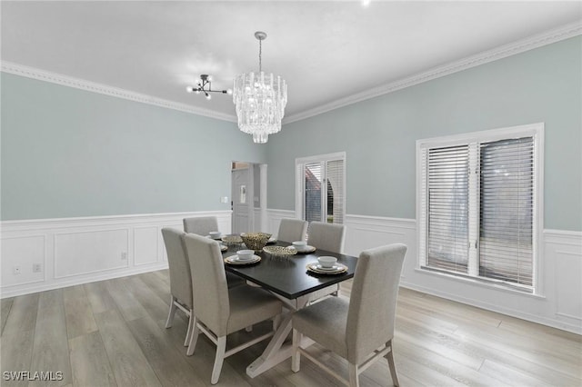 dining room with a notable chandelier, plenty of natural light, ornamental molding, and light wood-type flooring