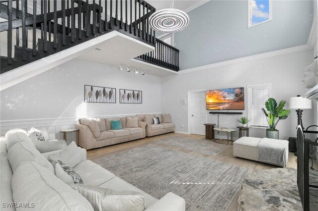 living room featuring crown molding, a towering ceiling, and wood-type flooring