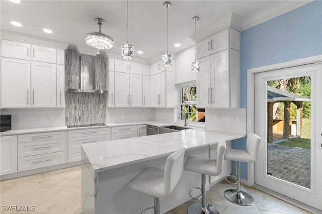 kitchen with white cabinetry, wall chimney range hood, sink, and kitchen peninsula