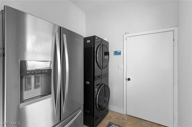 laundry room with light tile patterned flooring and stacked washer / drying machine