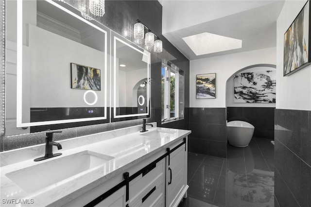 bathroom with vanity, tile walls, and a tub