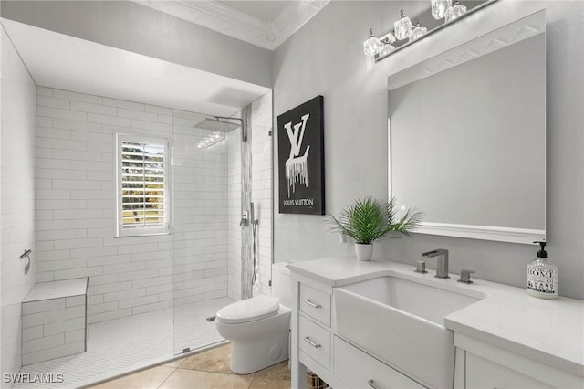 bathroom with vanity, a tile shower, ornamental molding, tile patterned floors, and toilet