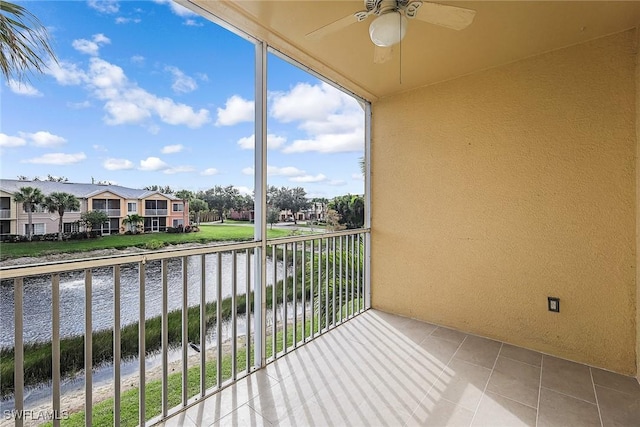 balcony with a ceiling fan, a water view, and a residential view
