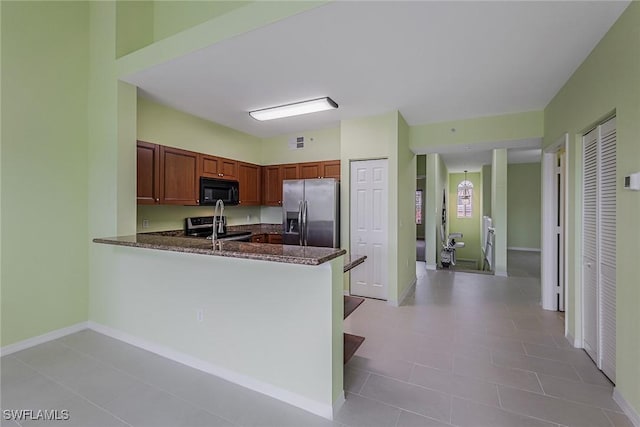 kitchen with stainless steel appliances, kitchen peninsula, and dark stone counters