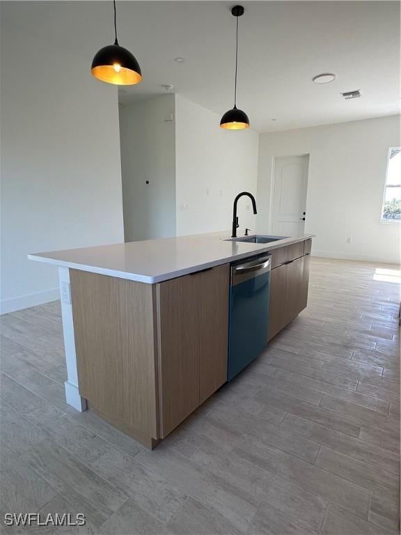 kitchen featuring pendant lighting, sink, dishwasher, and a center island with sink