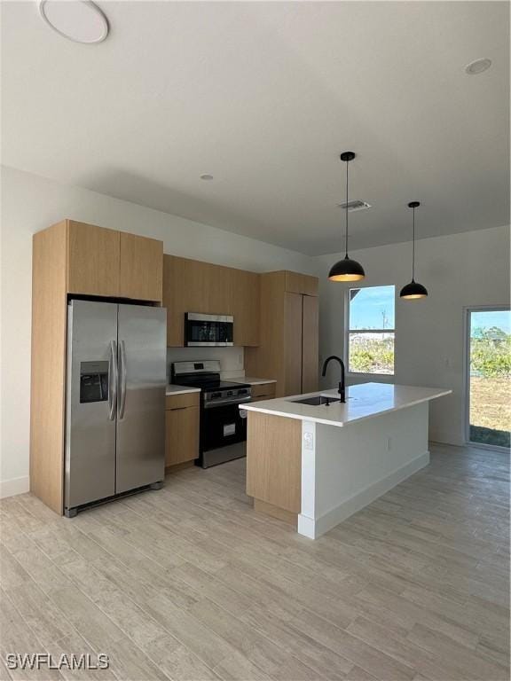 kitchen featuring sink, light hardwood / wood-style flooring, hanging light fixtures, a center island with sink, and stainless steel appliances