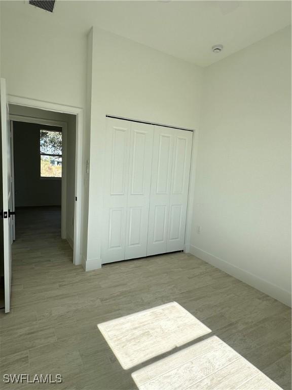 unfurnished bedroom featuring light hardwood / wood-style floors and a closet