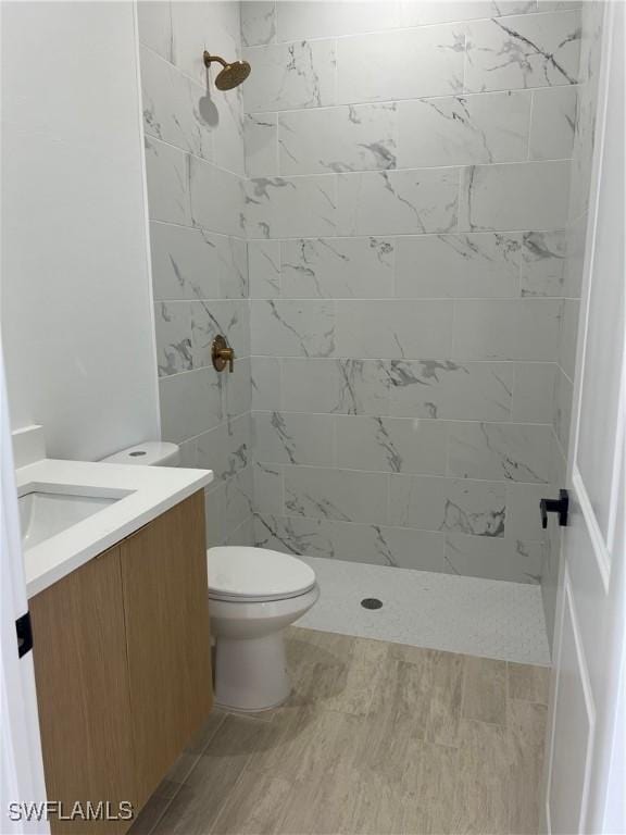 bathroom featuring tiled shower, vanity, and toilet