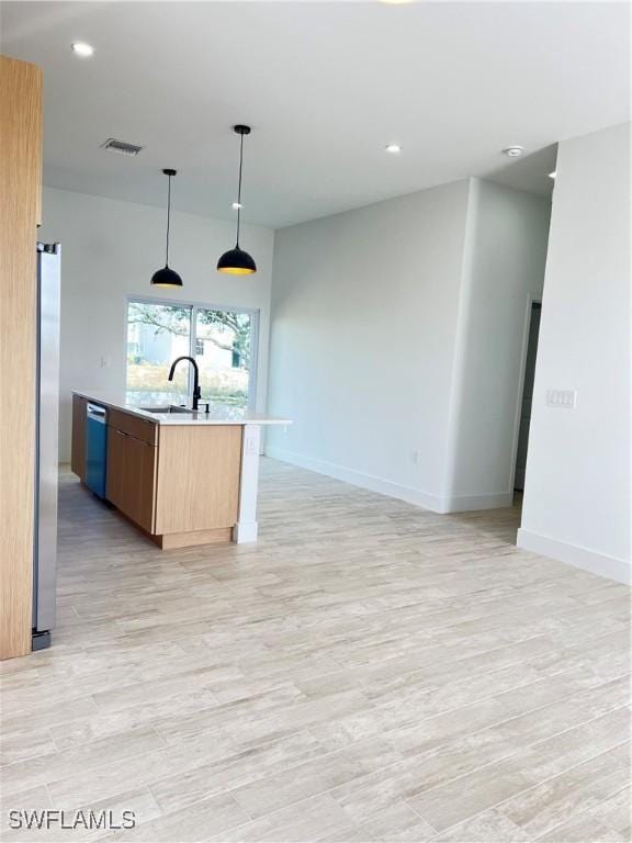 kitchen featuring sink, appliances with stainless steel finishes, a center island with sink, decorative light fixtures, and a barn door