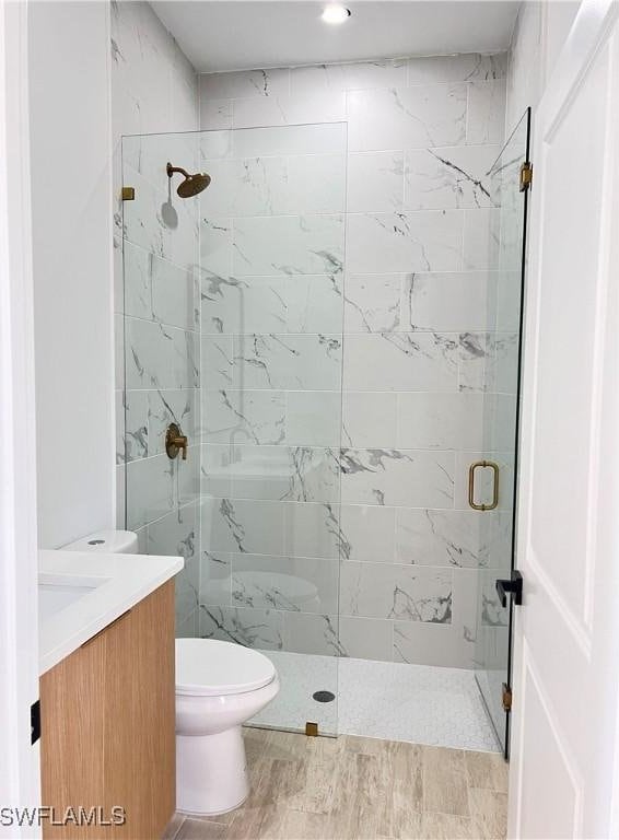 bathroom featuring vanity, hardwood / wood-style flooring, toilet, and walk in shower